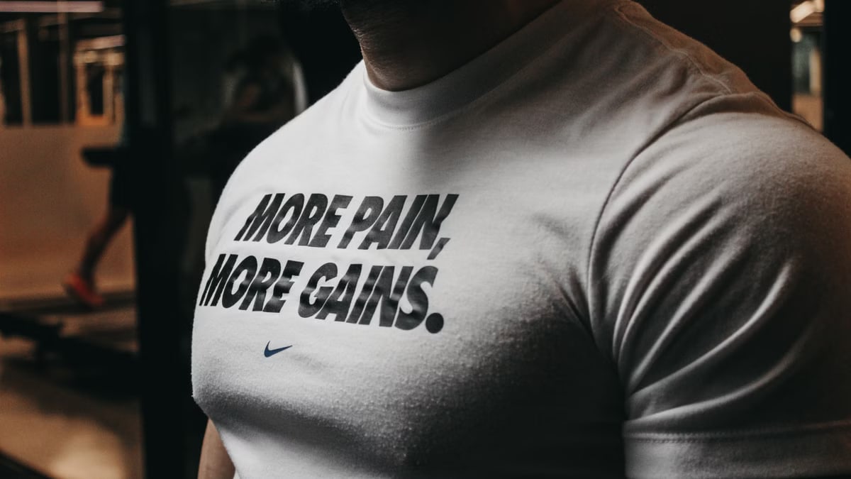 Close-up of a muscular man in the gym wearing a t-shirt with an inspiring fitness message.